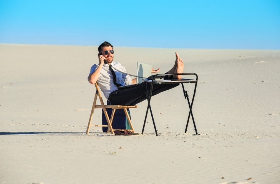 What moving your office to the beach looks like: man with a desk in the sand