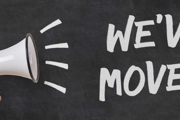 A chalkboard with the text WE'VE MOVED! booms from a megaphone, symbolizing an exciting business relocation notice.